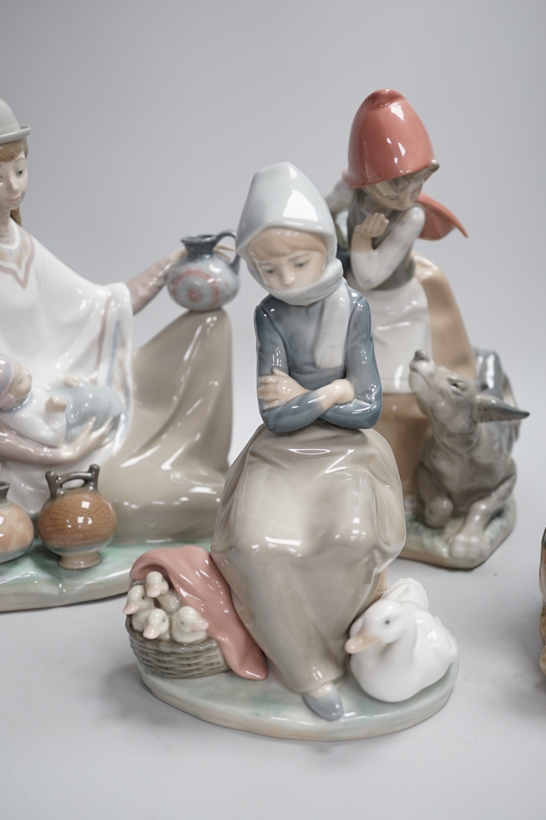 Four Lladro models, a girl potter, girl with ducks, mother and child with pottery and girl with a dog, highest 23.3cm